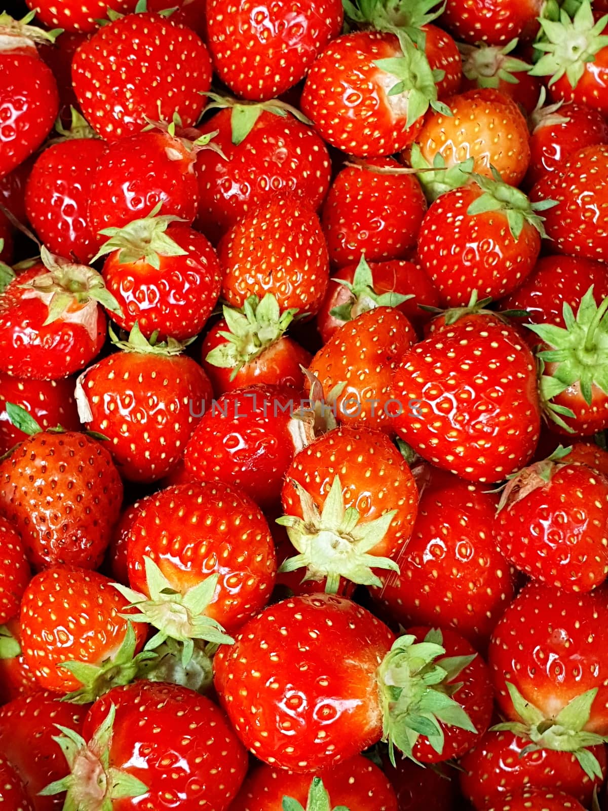 Full frame background with fresh whole strawberries with green leaves.