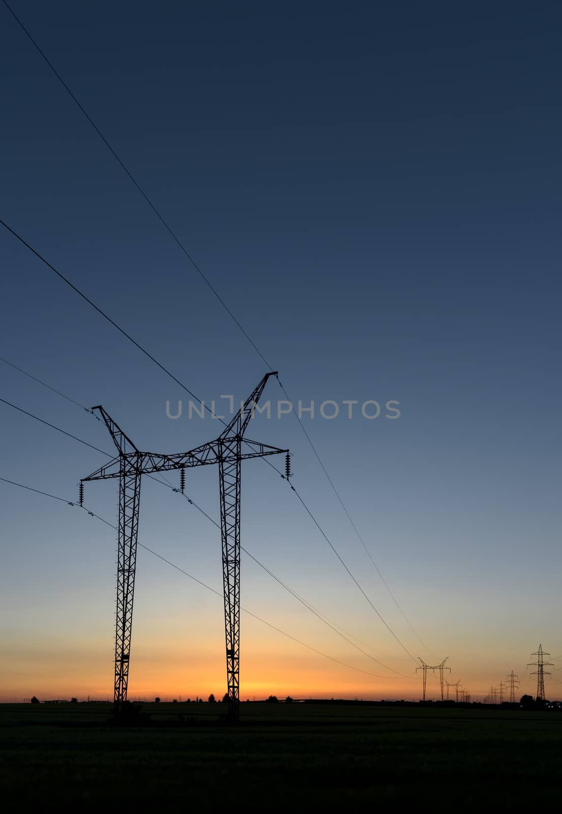 Large transmission towers at sunset with horizon