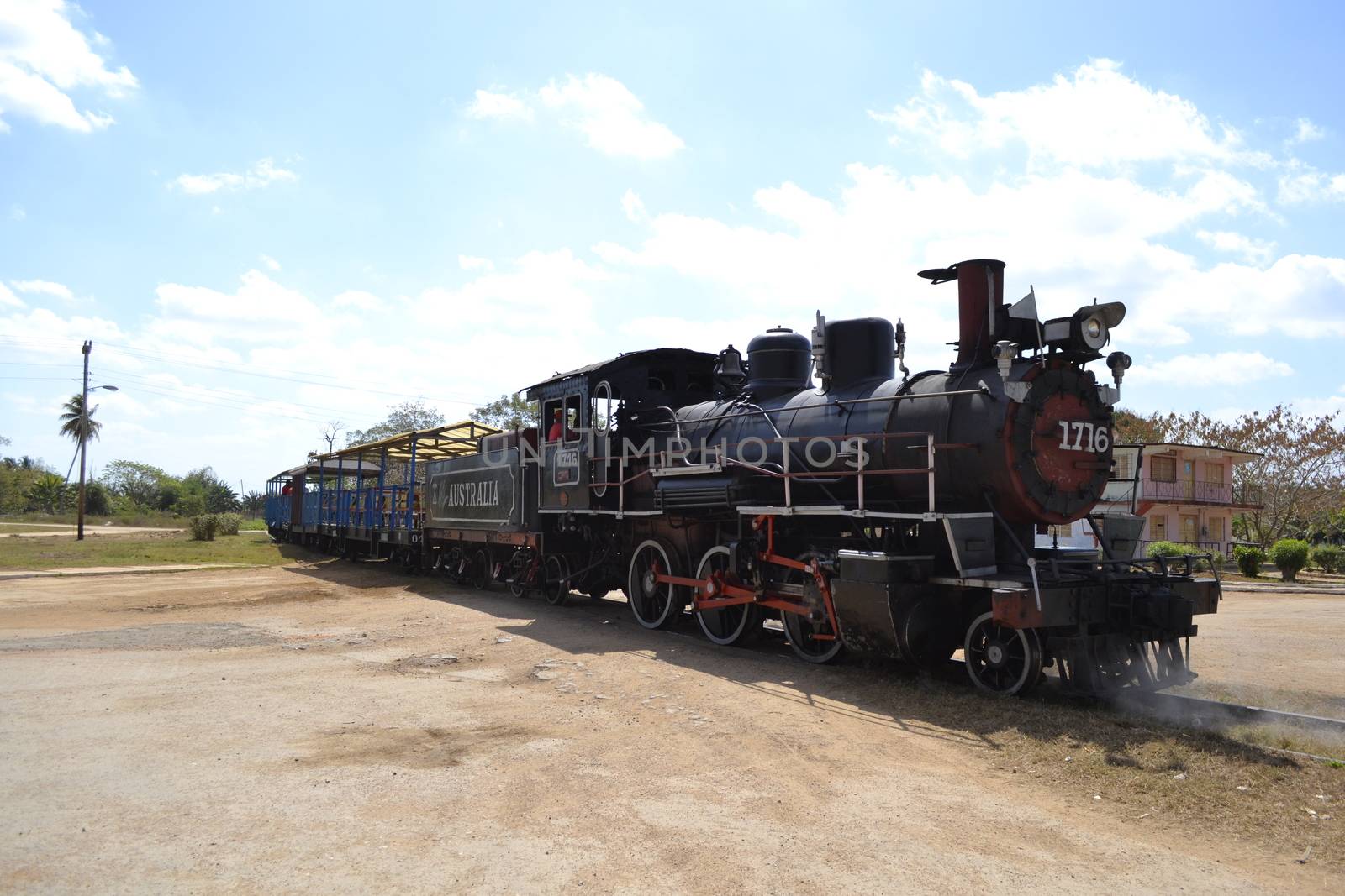 Trinidad, Cuba, February 2011: old steam train rom Trinidad to the Sugar Mills' Valley - Valle de los Ingenios in Cuba pulling in the city, crossing a dirt road.