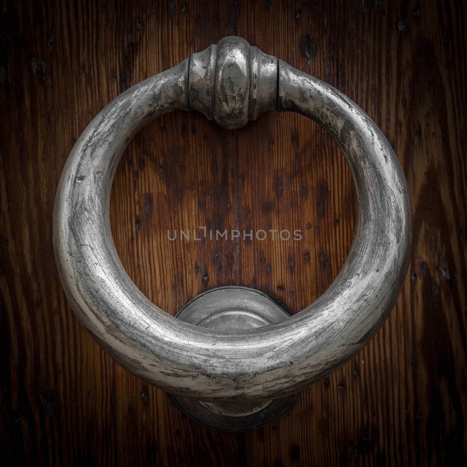 Old brass knocker on wooden door.