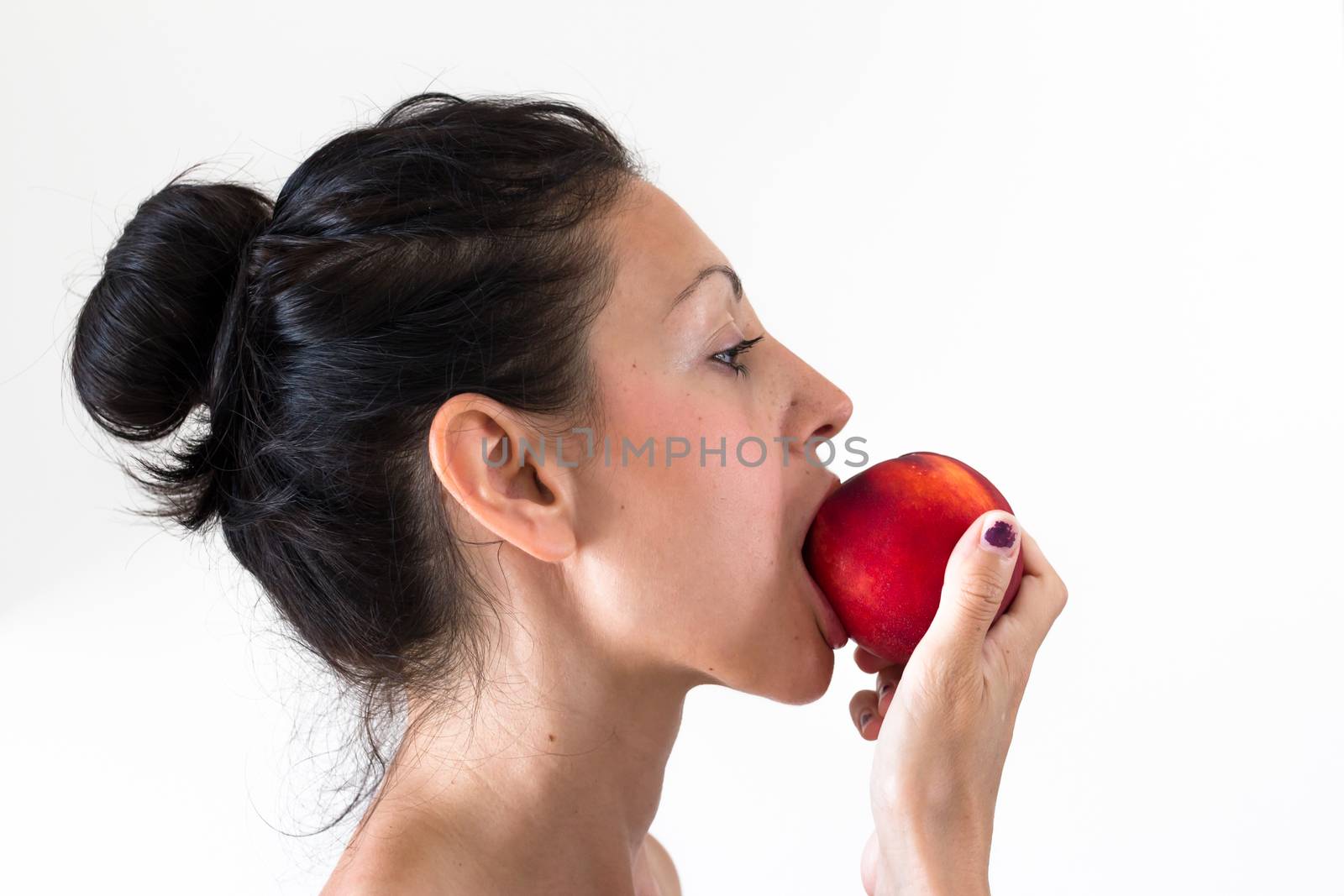 A girl while eating a peach, isolated on white background.