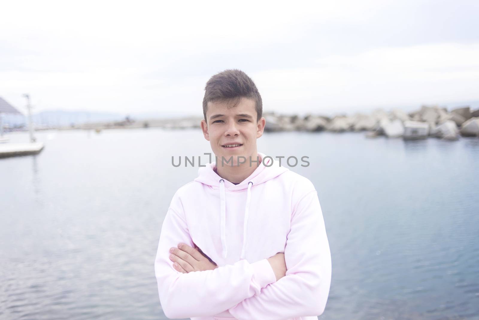Young teenager male with crossing arms standing on promenade while looking at camera by raferto1973