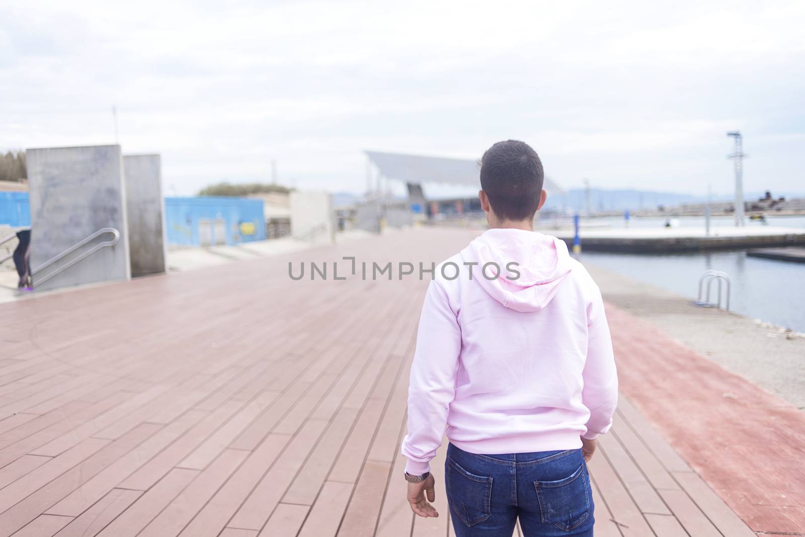 Young teenager male walking on promenade while looking at camera by raferto1973
