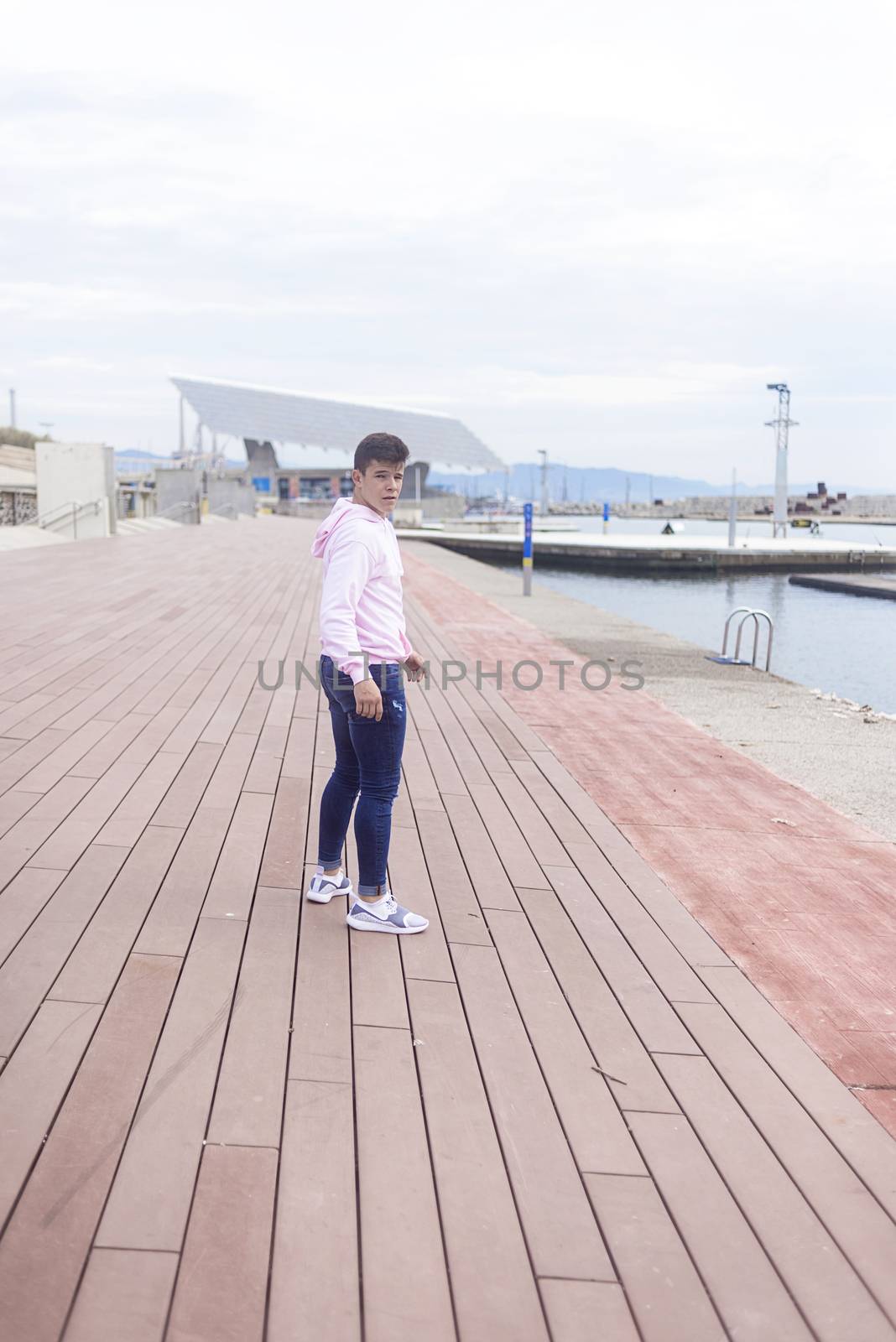 Young teenager walking on promenade while looking at camera