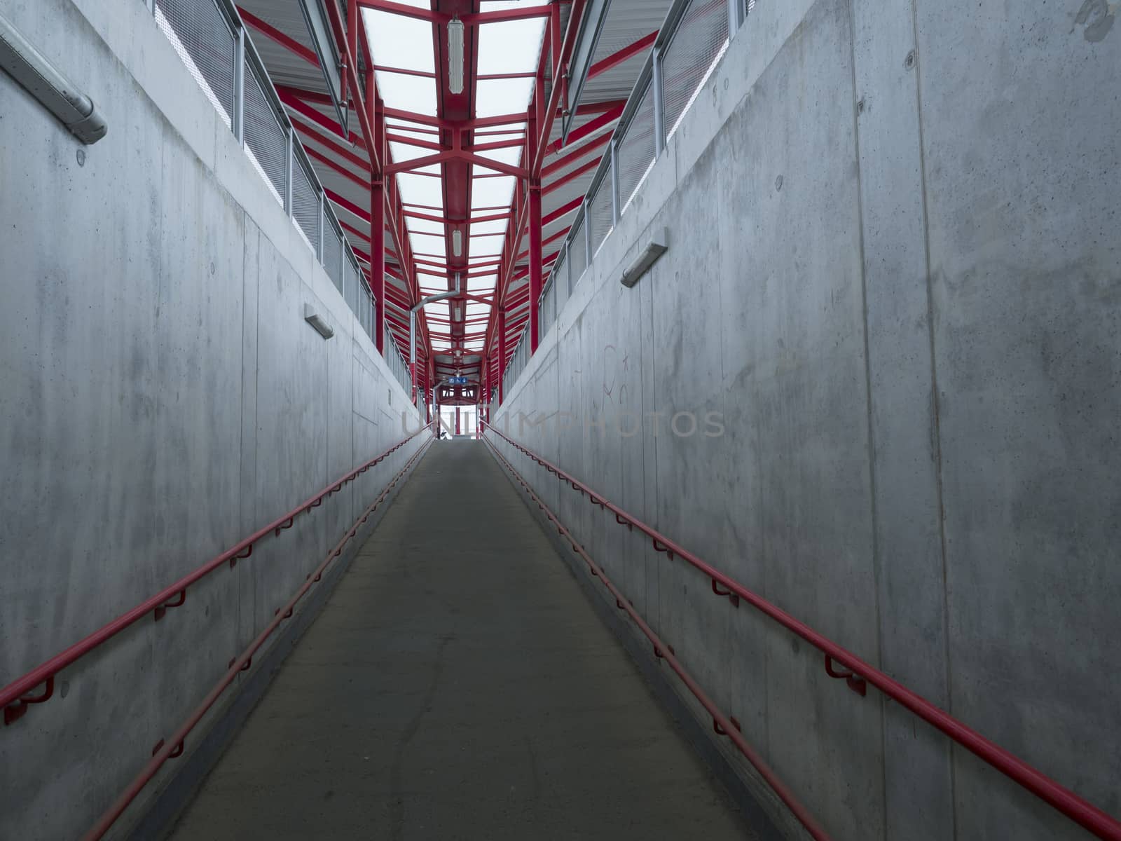 Empty concrete undergound passage platform subway on train station, gray and red, diminishing perspective.