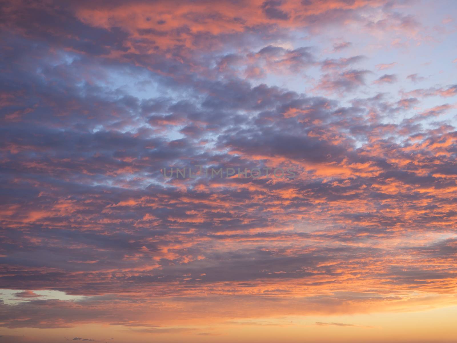 Texture, background, pattern. Sunset or dawn colored tropical clouds, red, pink, blue, orange and yellow pastel colors. Romantic sky at dusk with dynamic dramatic expressive clouds by Henkeova