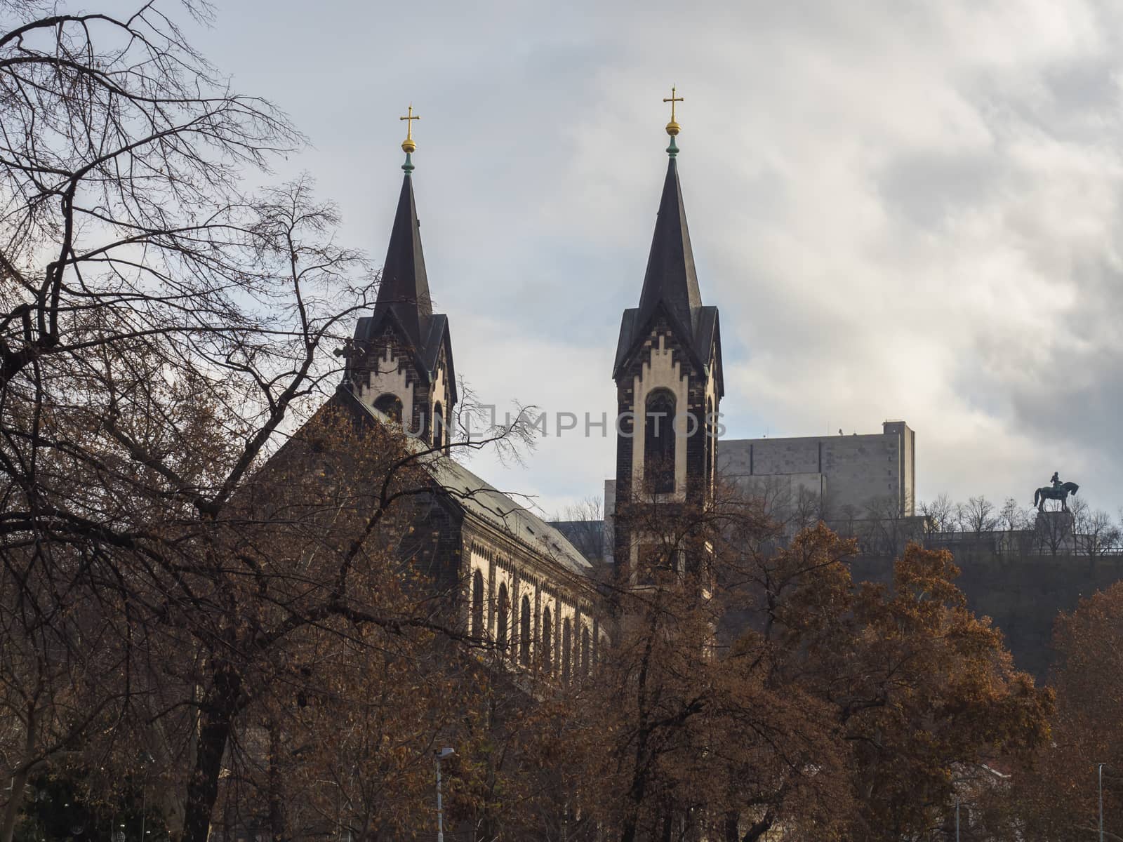 Saints Cyril and Methodius gothic church and National Monument at Vitkov with Equestrian Statue of Jan Zizka viewed from Karlinske namesti square park with late autumn trees. Czech Republic, Prague.
