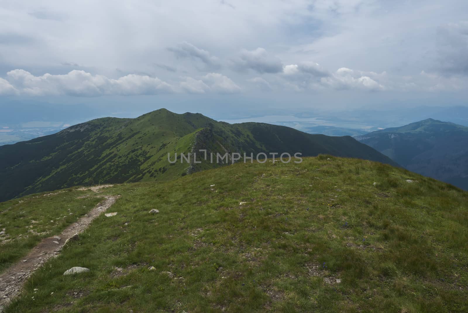 View from Banikov peak on Western Tatra mountains or Rohace panorama. Sharp green mountains - ostry rohac, placlive and volovec with hiking trail on ridge. Summer blue sky white clouds