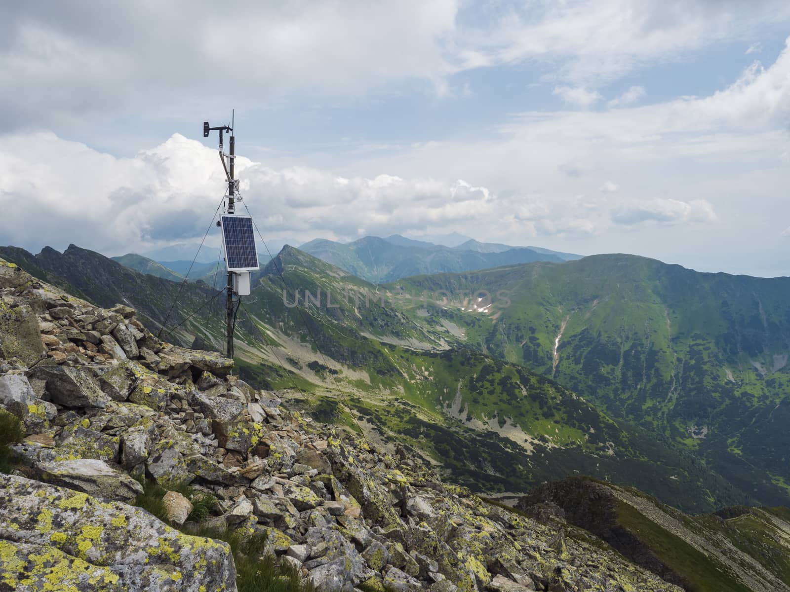 Top of the peak Banikov at Western Tatra mountains or Rohace. Sharp green mountains - ostry rohac, placlive and volovec with hiking trail on ridge. Summer blue sky white clouds