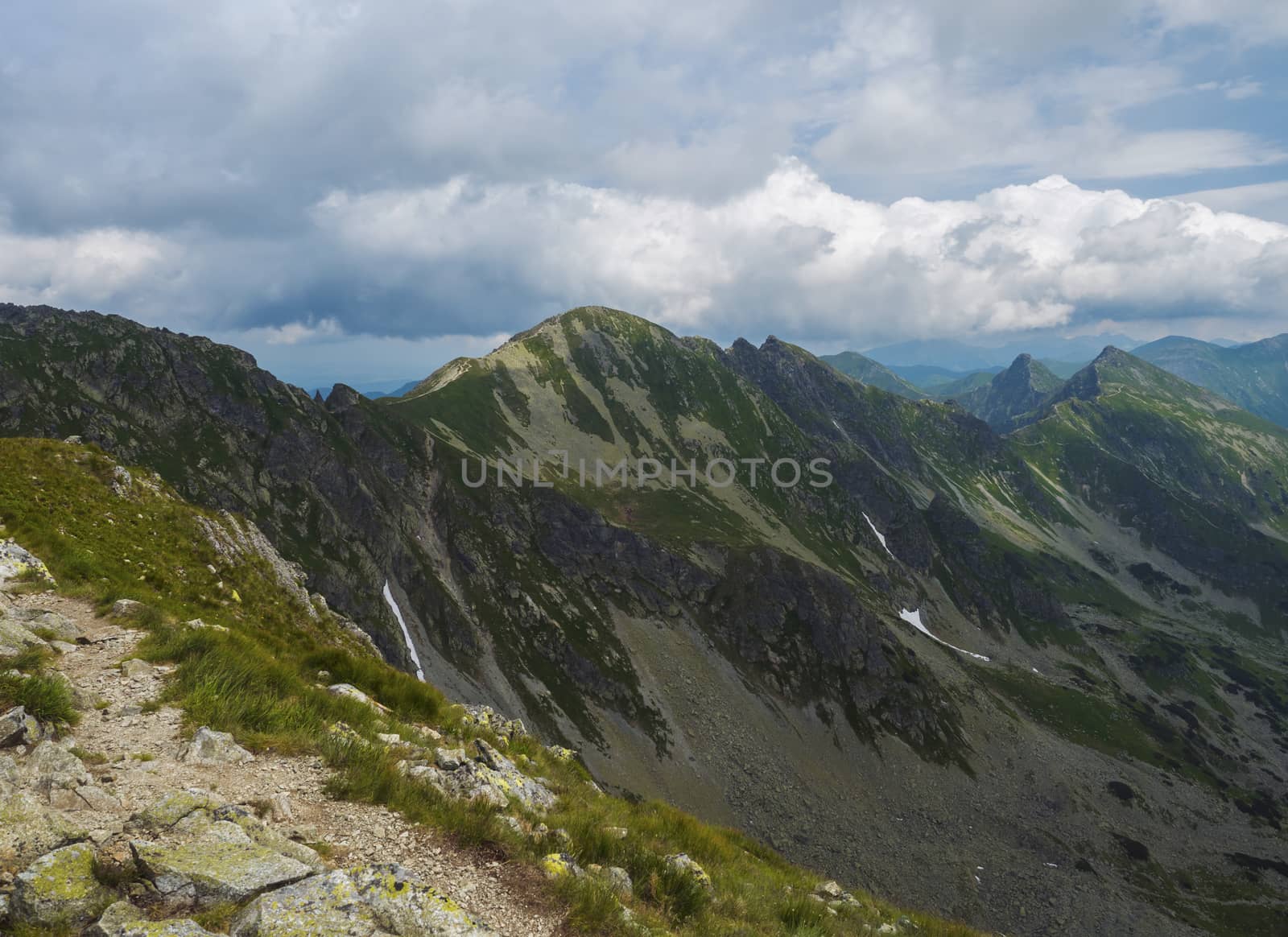 View from Banikov peak on Western Tatra mountains or Rohace panorama. Sharp green mountains - ostry rohac, placlive and volovec with hiking trail on ridge. Summer blue sky white clouds