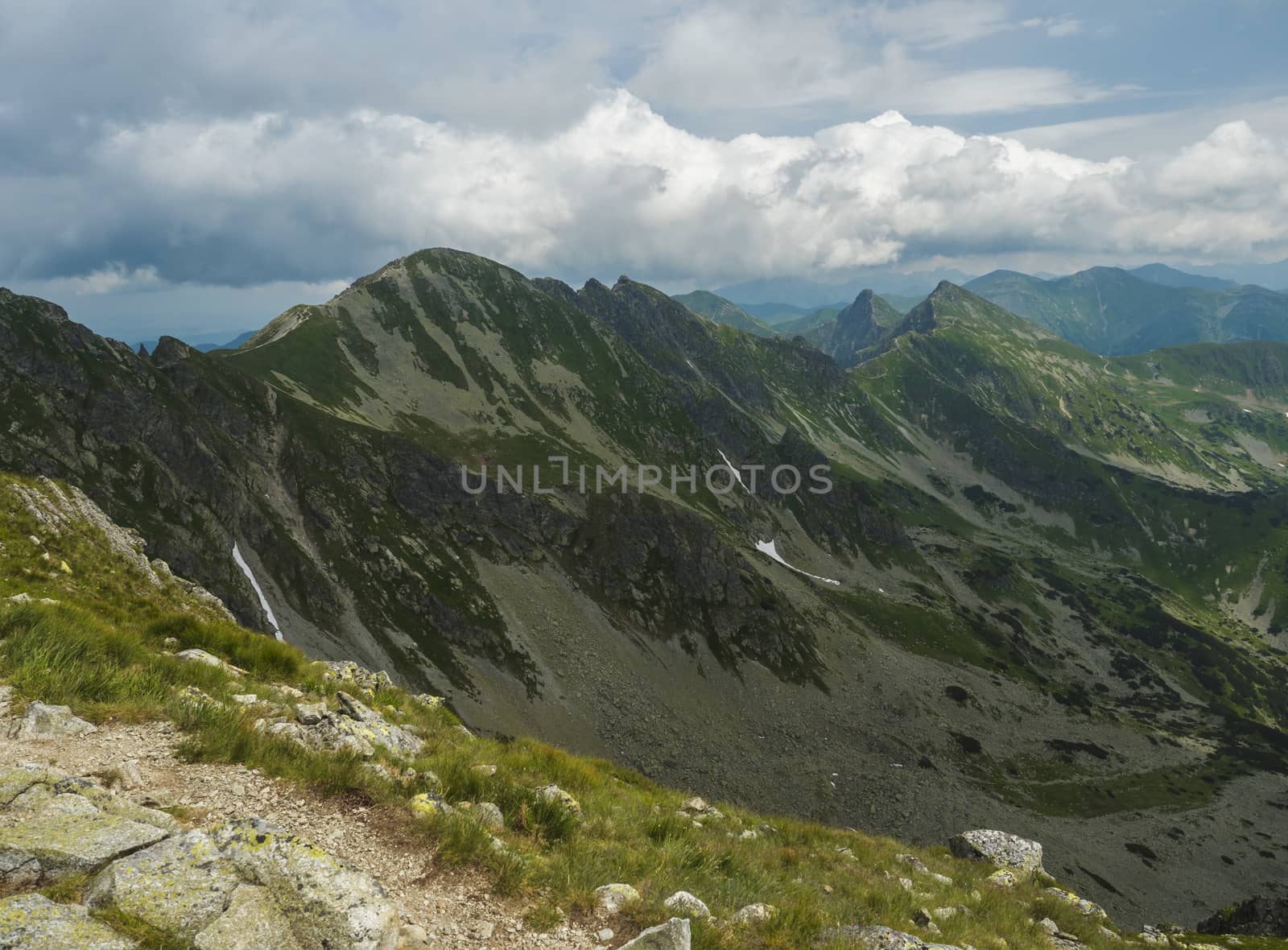 View from Banikov peak on Western Tatra mountains or Rohace panorama. Sharp green mountains - ostry rohac, placlive and volovec with hiking trail on ridge. Summer blue sky white clouds