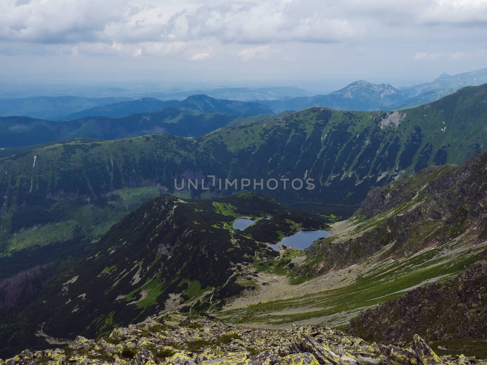 view from Banikov peak on Western Tatra mountains or Rohace panorama. Sharp green mountains ostry rohac, placlive and volovec and mountain lake Rohacska plesa. Summer blue sky white clouds