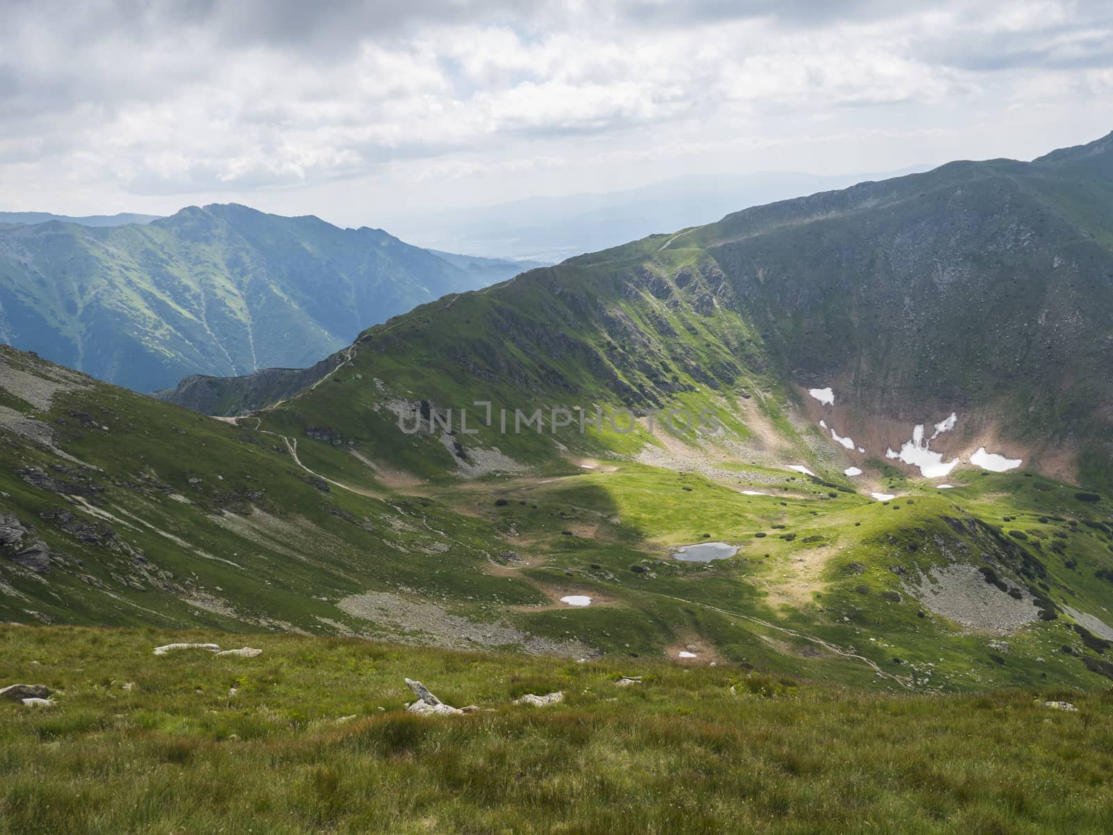 view from Ostry Rohac peak on Western Tatra mountains or Rohace panorama. Sharp green mountain peaks with hiking trail on ridge. Summer blue sky white clouds