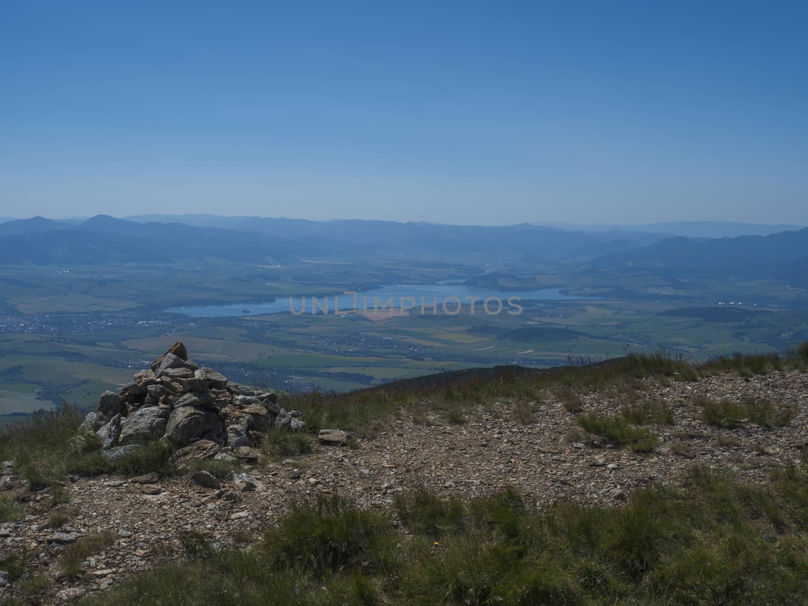 view on valley of Liptovsky Mikulas with liptovska mara lake from hiking trail on Baranec peak at Western Tatra mountains or Rohace. Summer blue sky background.