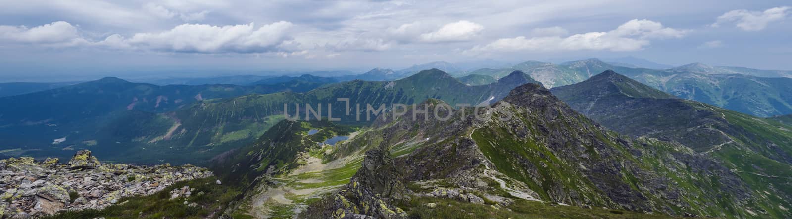 Panoramic view from Rohac peak on Western Tatra mountains or Rohace panorama with hiking trail on ridge. Sharp green mountains and mountain lakes Jamnicke plesa. Summer blue sky white clouds