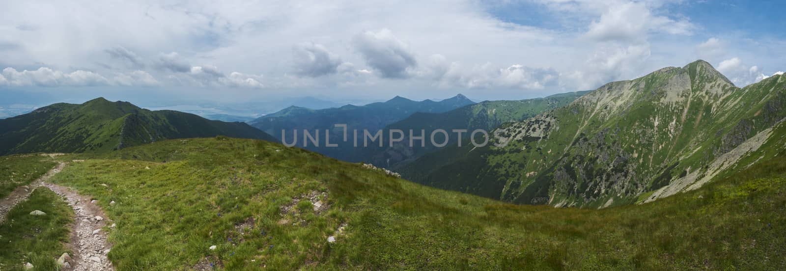 Beautiful panoramic mountain landscape, view from Banikov peak on Western Tatra mountains or Rohace panorama. Sharp green grassy mountains with hiking trail on ridge. Summer blue sky white clouds