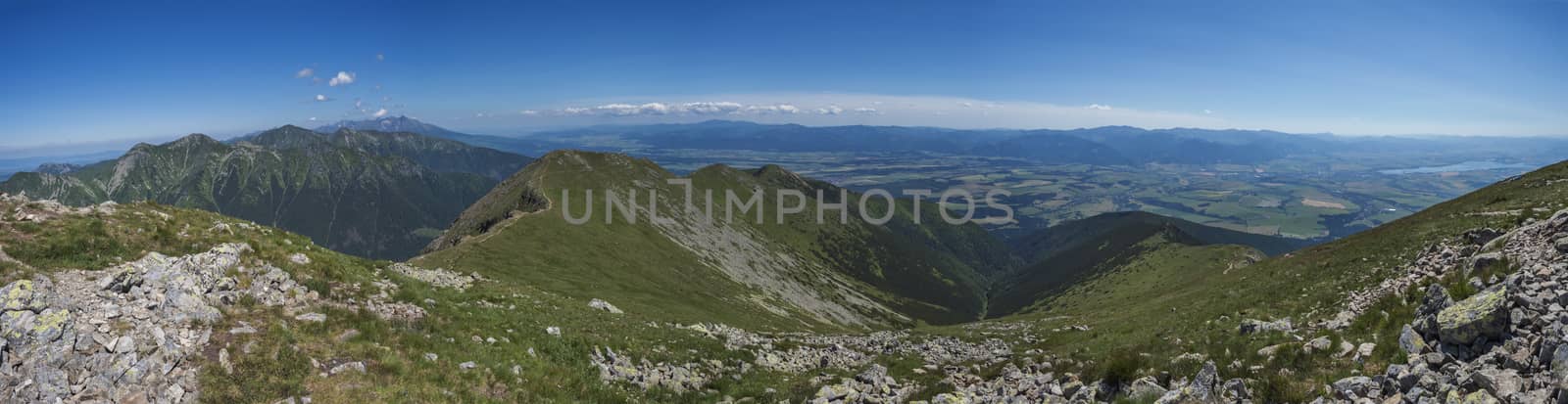 wide panoramic view with top of Baranec peak on Western Tatra mountains or Rohace panorama. Sharp green mountains with hiking trail on ridge. and Liptov valley. Summer blue sky background.