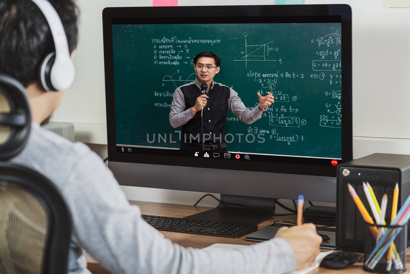 Rear View of Asian student learning with teacher over the physics formular in thai laguage on black board via video call conference when Covid-19 pandemic, education and Social distancing concept