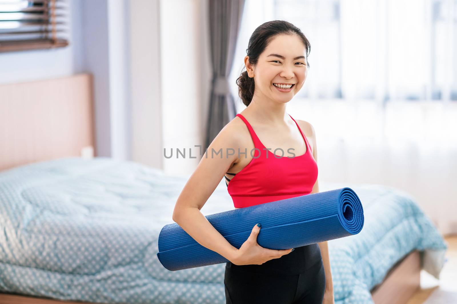 Portrait of Asian woman holding the Yoga mat before practicing yoga from home when Covid19 outbreak and lockdown, workout at home, coronavirus pandemic and quarantine,sports and healthcare concept