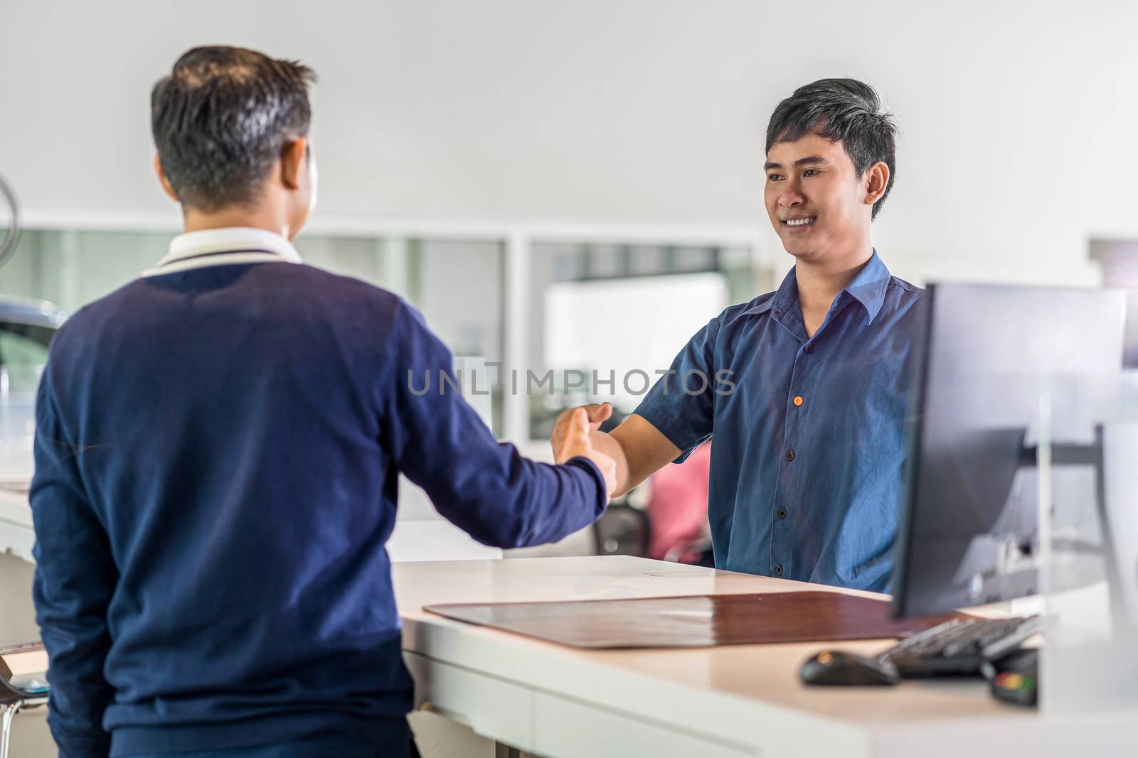 Asian Mechanic handshake with the customer and leader in maintenance service center which is a part of showroom, business and customer care concept