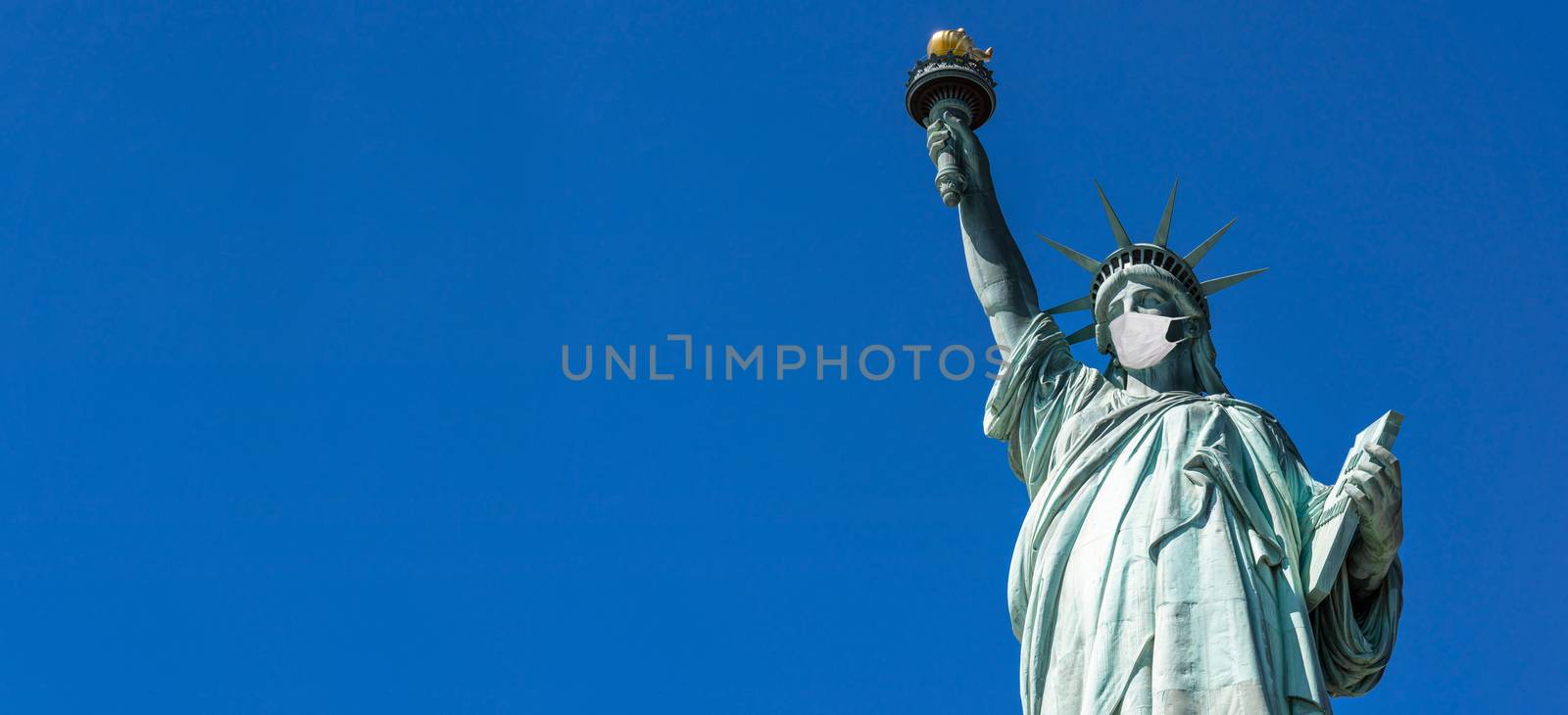 The Statue of Liberty wearing surgical mask when Covid-19 Outbreak over panorama or banner blue color background, New York city, USA,coronavirus pandemic,Architecture and building with tourist concept