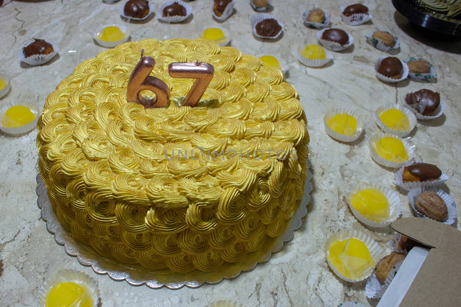 Golden birthday cake covered in chantilly surrounded by sweeties