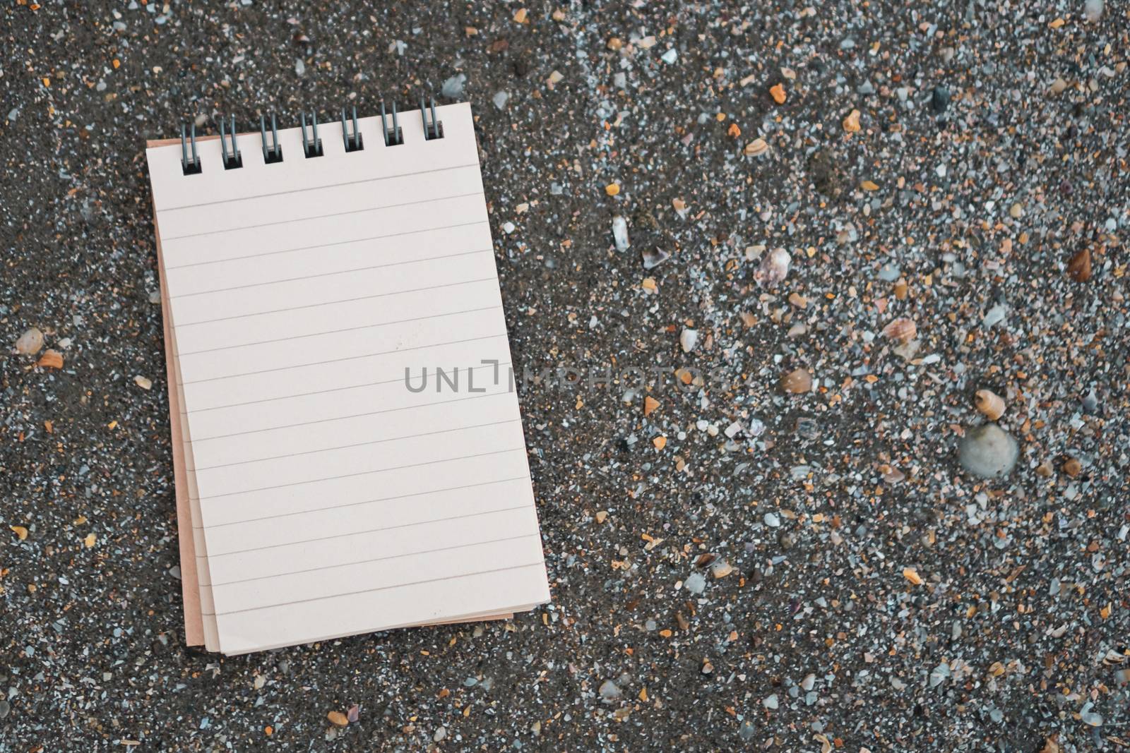 Small white notebook on sand at beautiful beach sea texture background.