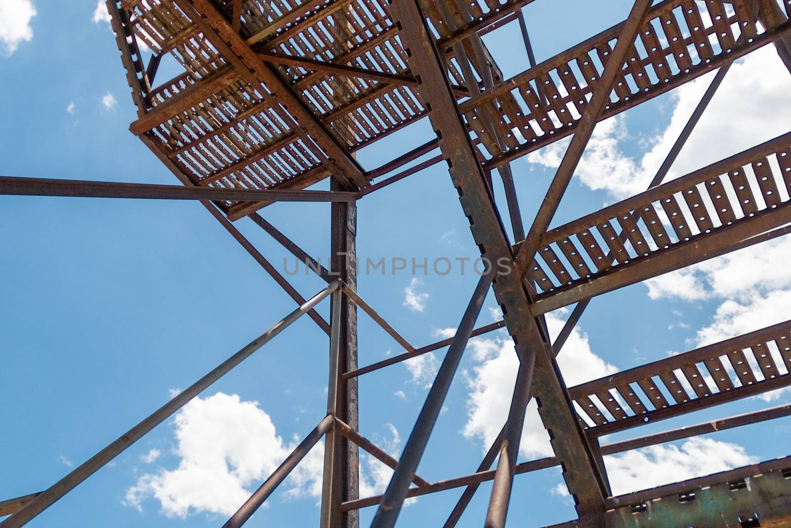 old rusty metal ladder in a blue sky with clouds