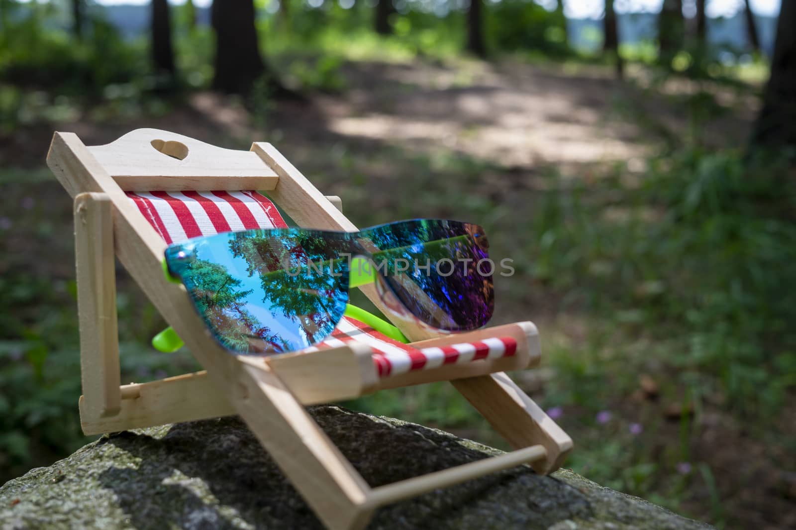 Sunglasses on a small striped deck chair in a concept of a summer vacation