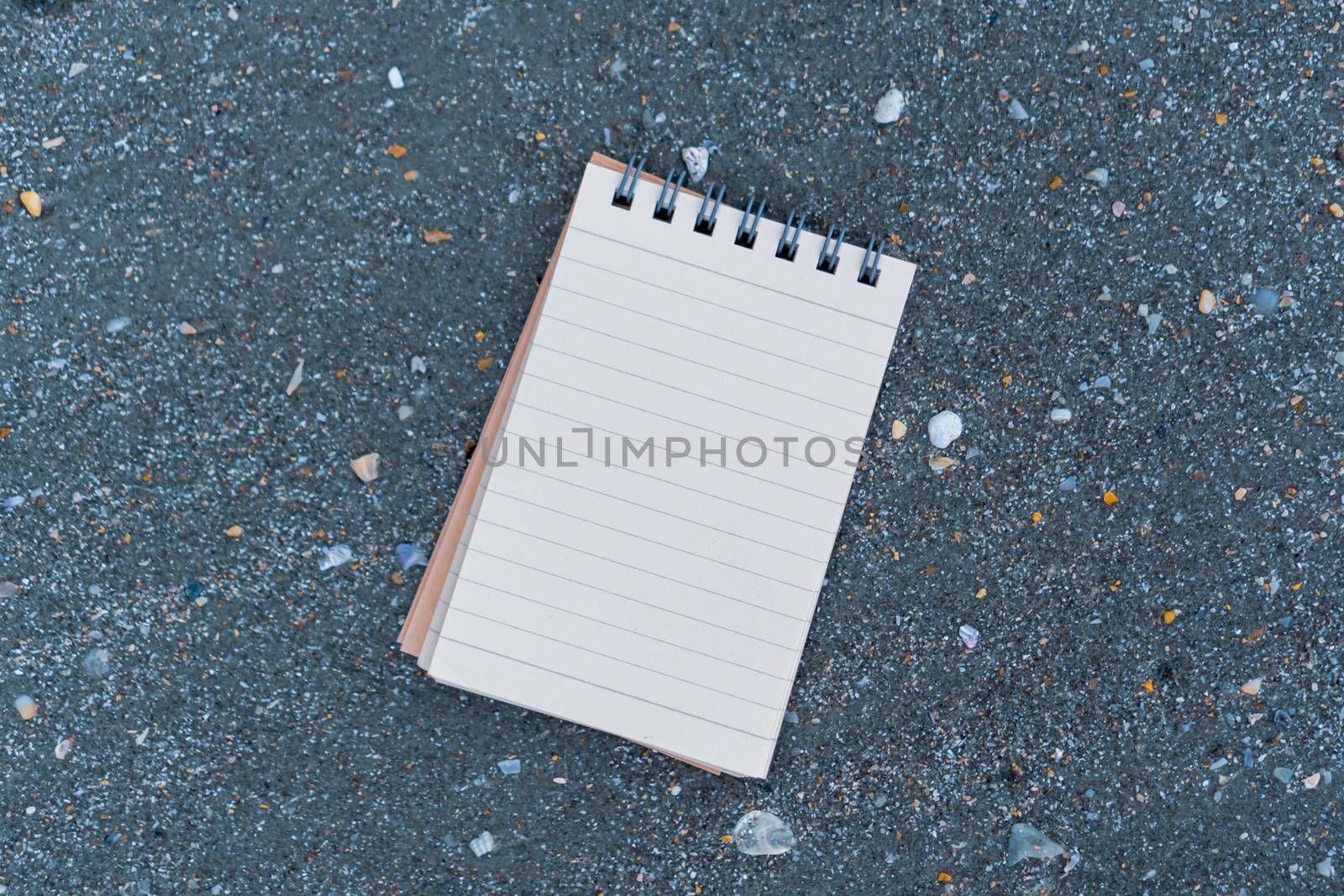 Small white notebook on sand at beautiful beach sea texture background.