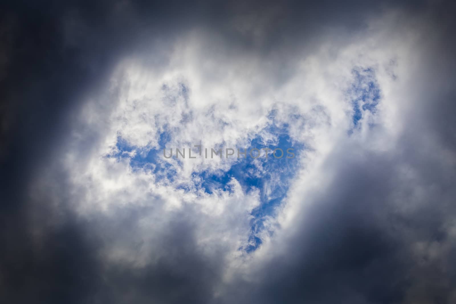 Incoming storm close-up cloudscape at march daylight in continental europe. Horse like form gap in dence cloud, captured with telephoto lens.