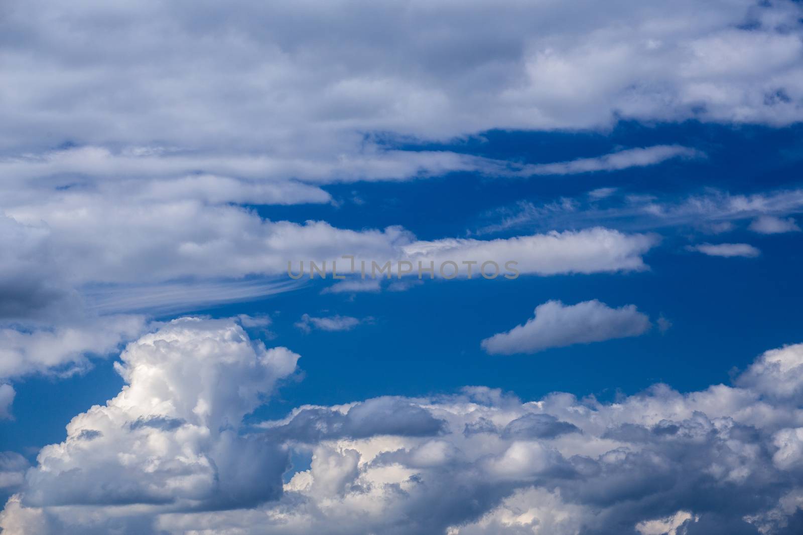 Regular spring clouds on blue sky at daylight in continental europe. Shot wit telehoto lens and circular polarizing filter.