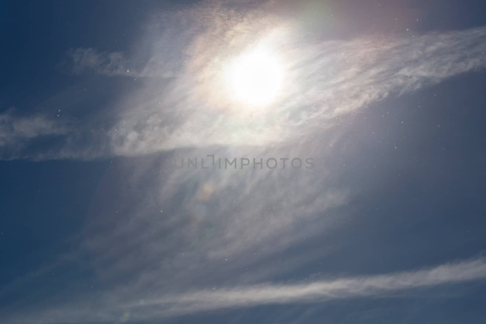 dust particles on blue sky with sun and feather cloud at spring day.
