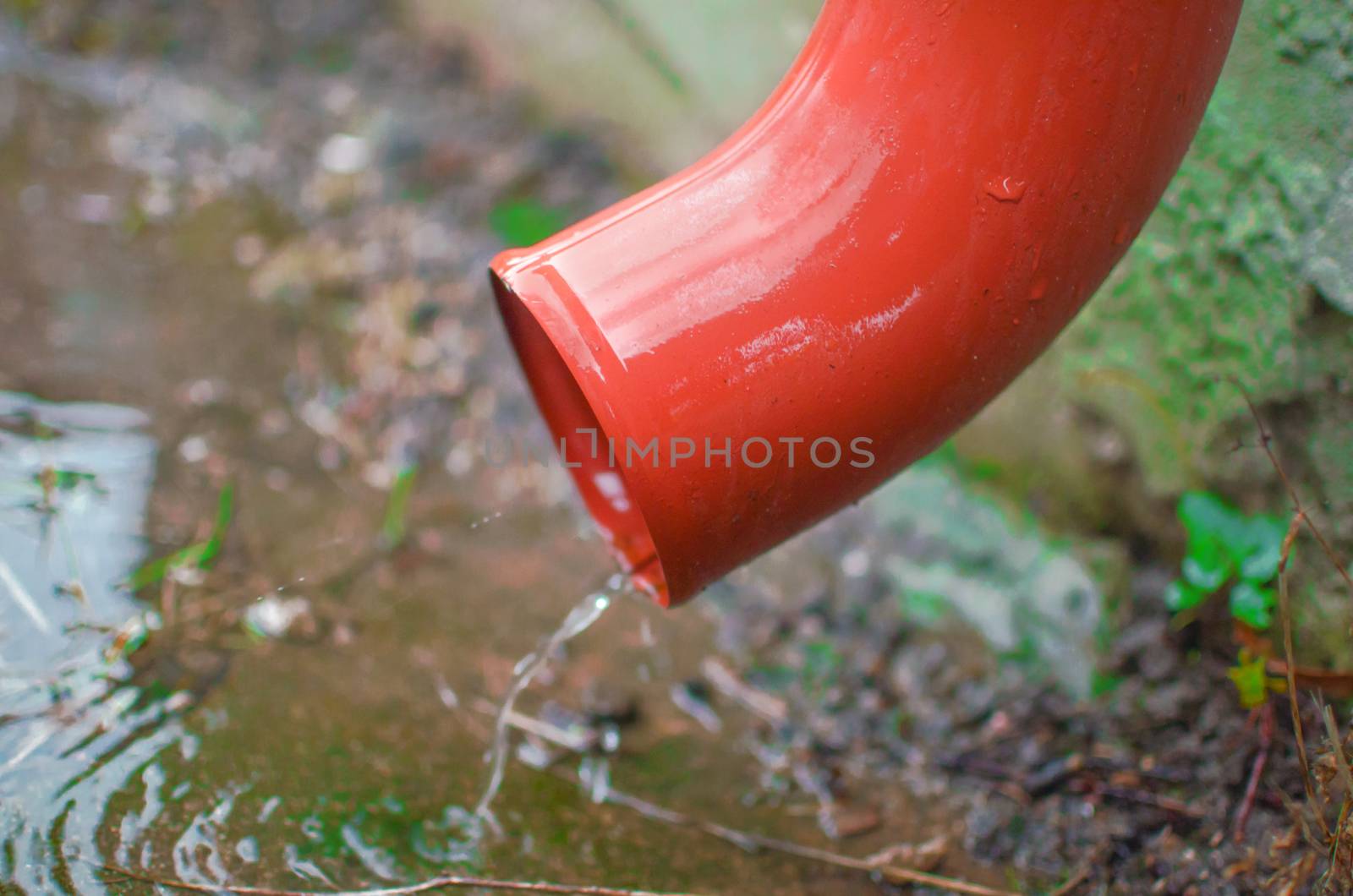 Rain water flowing from drain pipe closeup by KajaNi