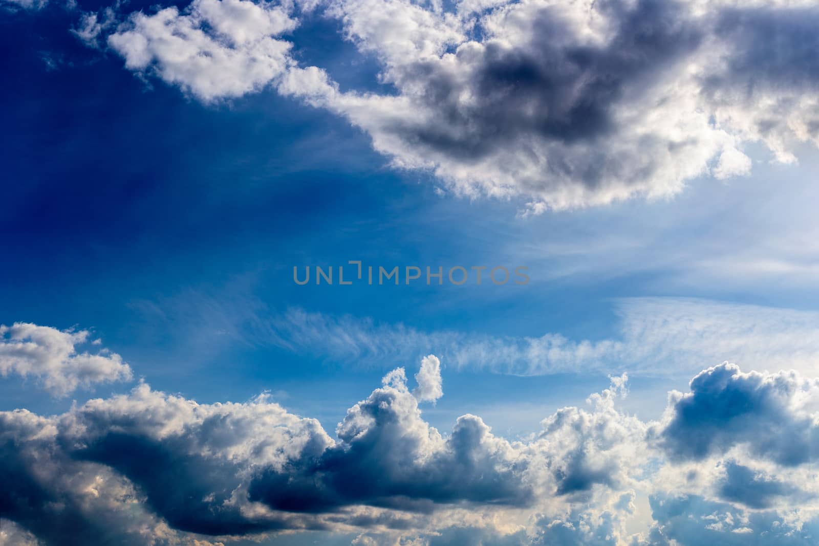 distant misty backlit cumulus and feather clouds near horizon closeup telephoto shot with polarizing effect
