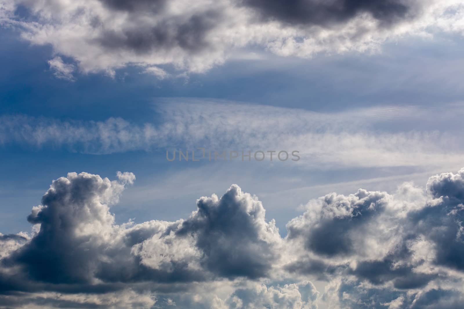 distant misty backlit cumulus and feather clouds near horizon closeup telephoto shot with polarizing effect
