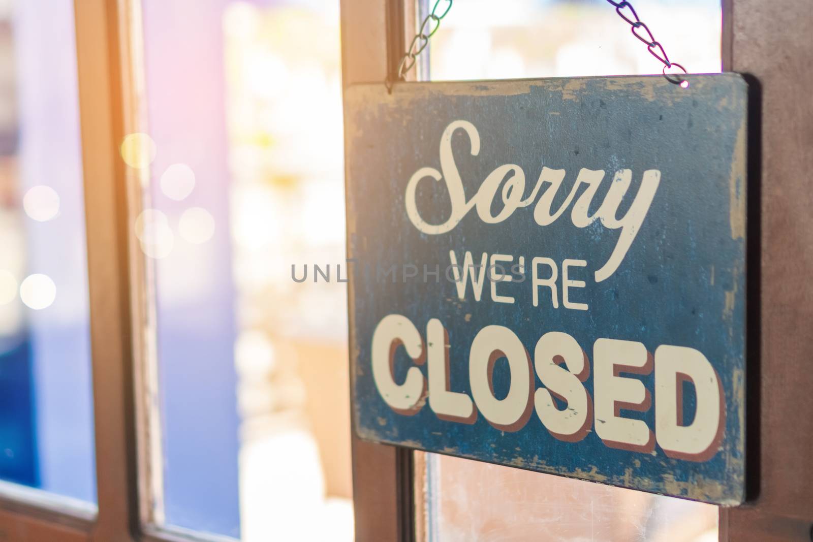 A Sign board of sorry we are closed hang on door of business shop with nature green background