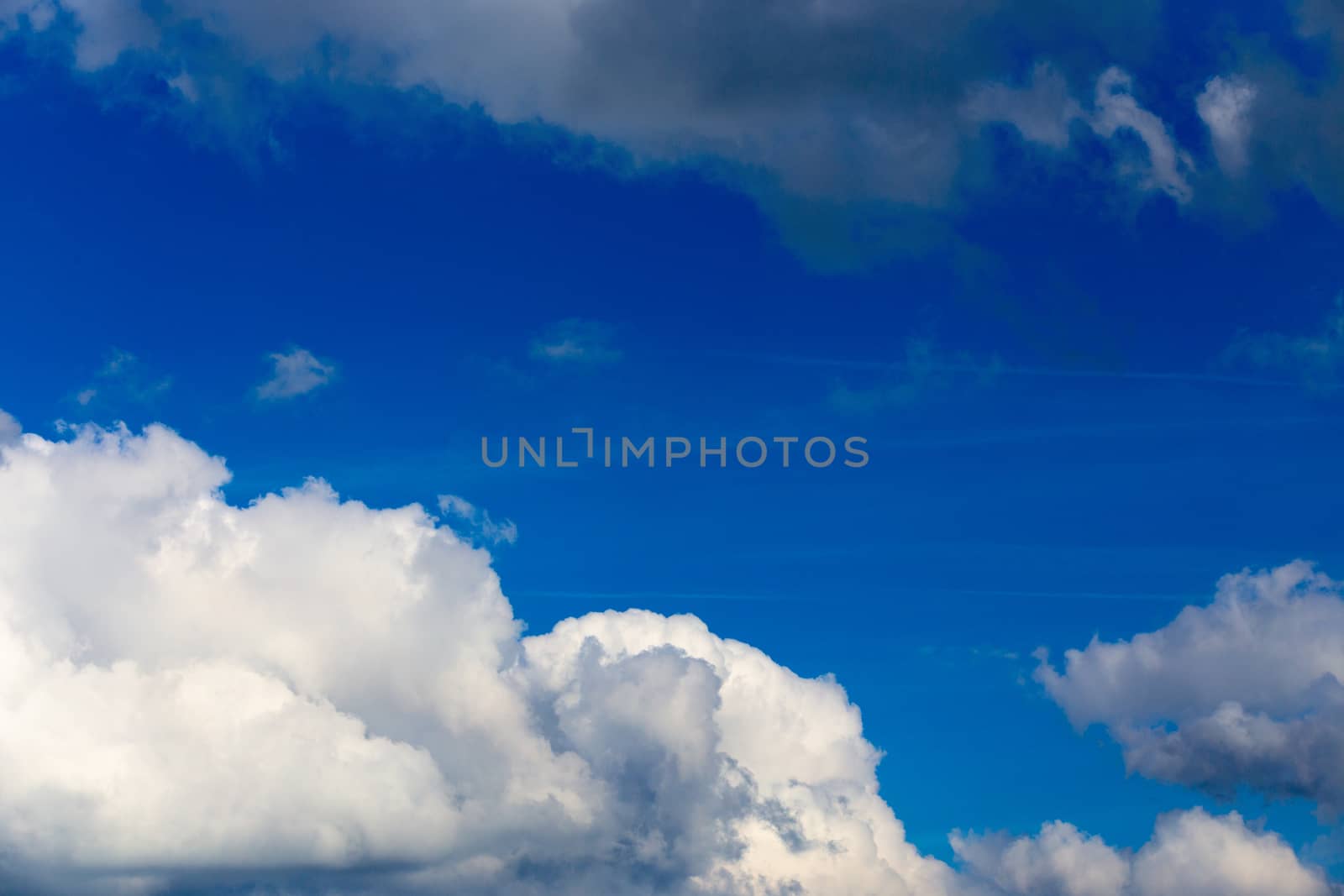 Regular spring clouds on blue sky at daylight in continental europe. Close shot wit telephoto lens and circular polarizing filter.