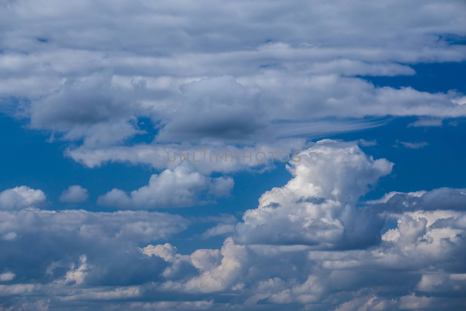 Regular spring clouds on blue sky at daylight in continental europe. Shot wit telehoto lens and circular polarizing filter.