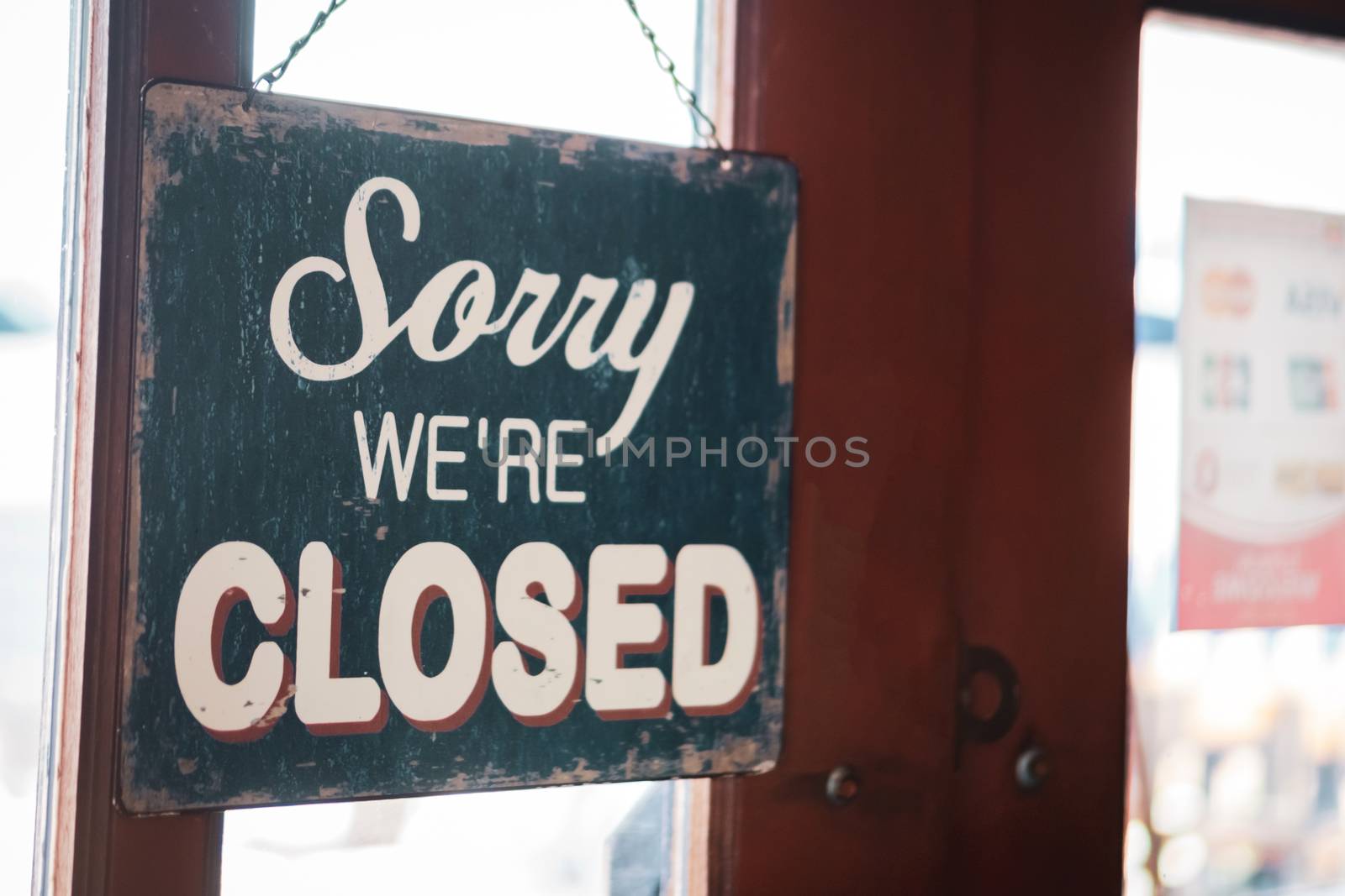 A Sign board of sorry we are closed hang on door of business shop with nature green background