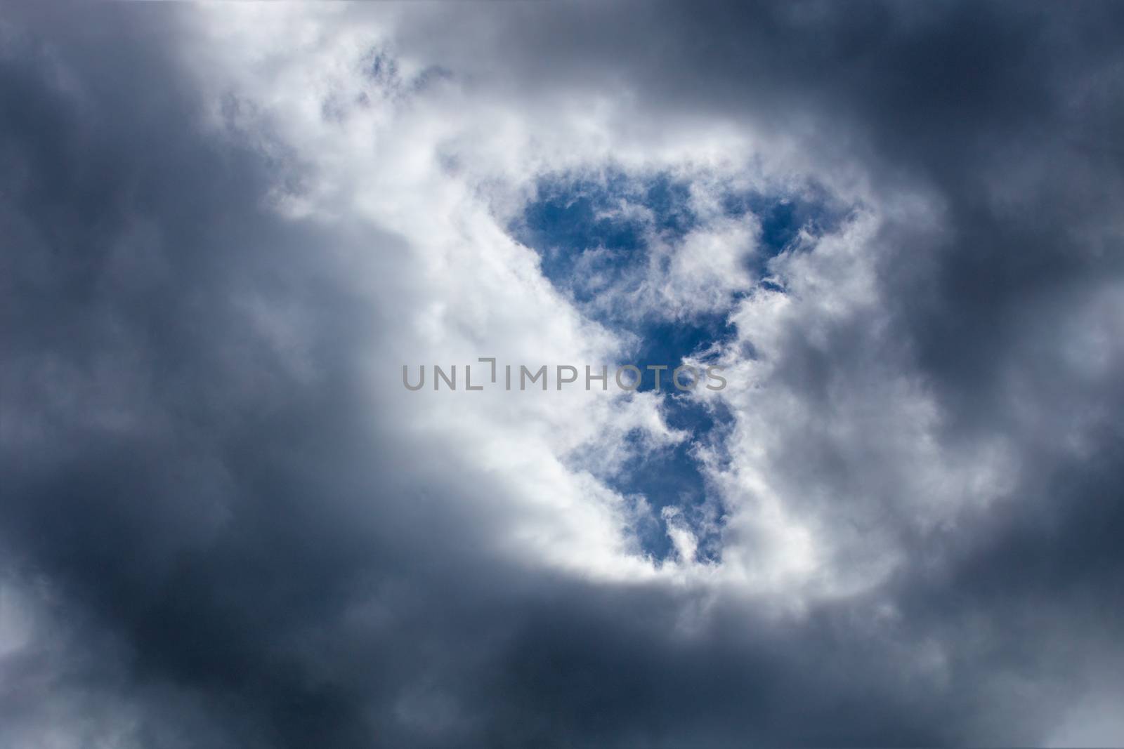 Incoming storm close-up cloudscape at march daylight in continental europe. T-form gap in dence cloud, captured with telephoto lens.
