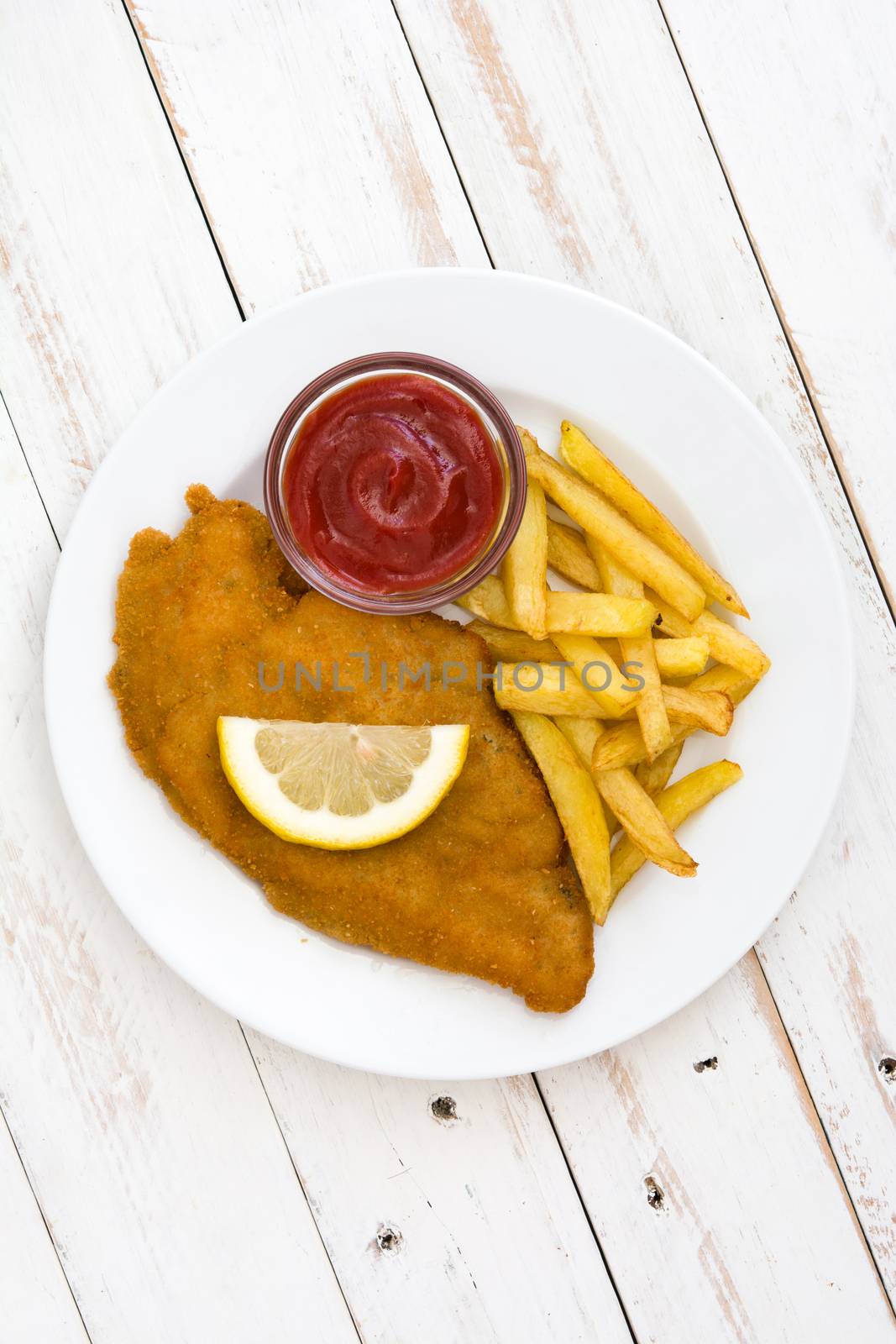 Wiener schnitzel with fried potatoes on white wooden background