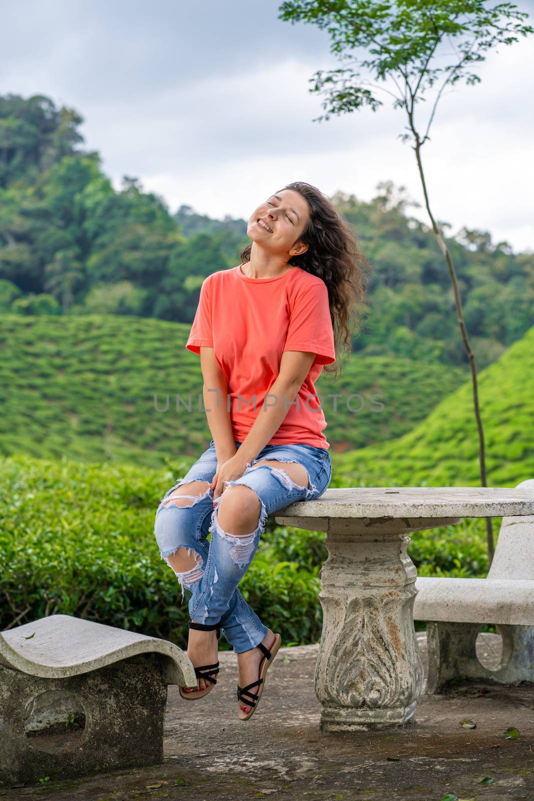 Beautiful brunette girl posing in the middle of the tea valley between green tea bushes