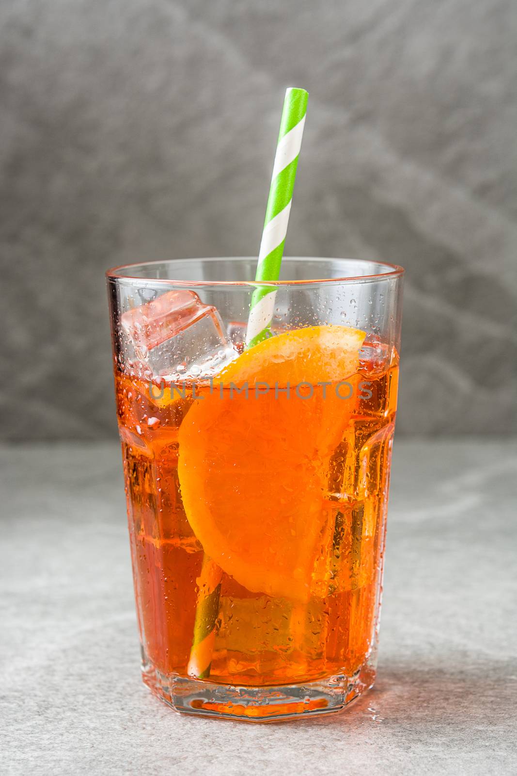 Aperol spritz cocktail in glass on gray stone by chandlervid85