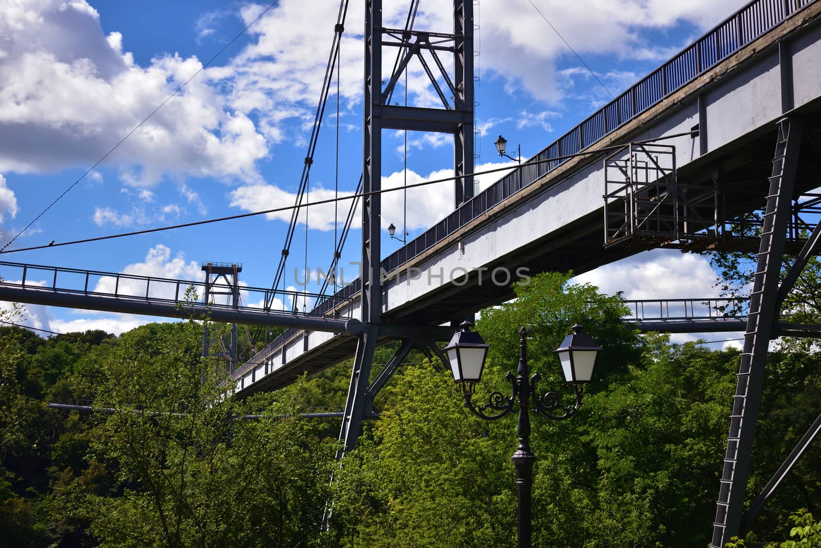 Pedestrian bridge, tree crowns and cloudy sky