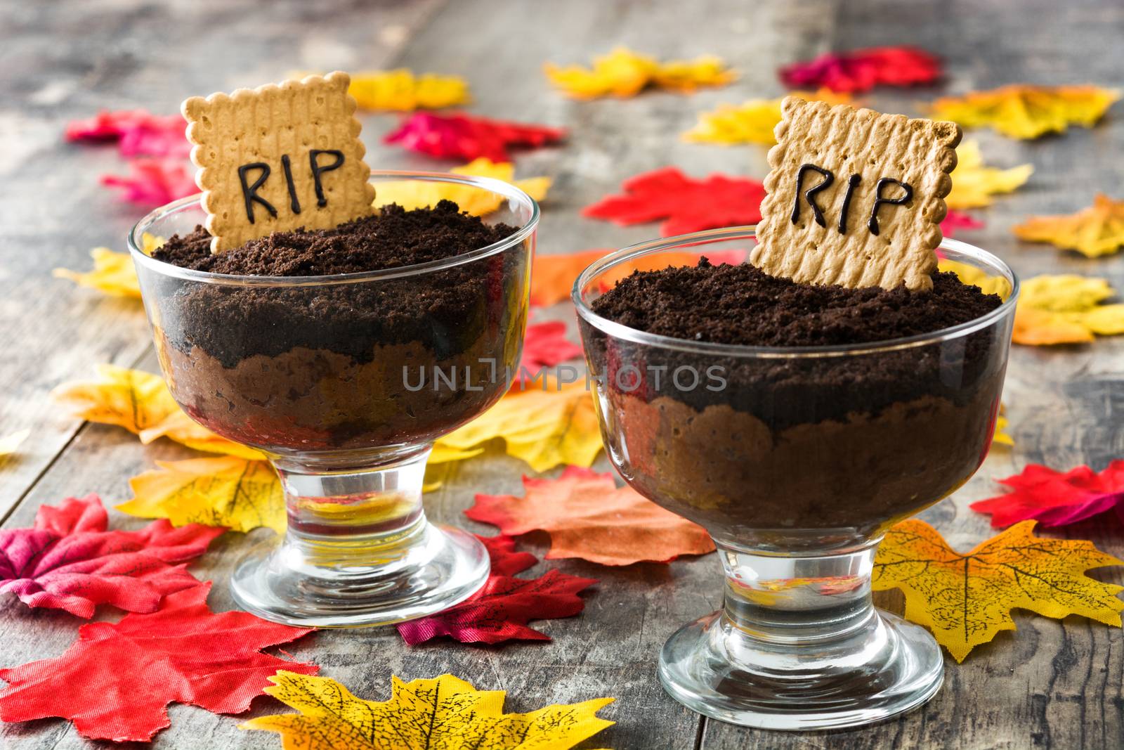 Funny Halloween chocolate mousse with tomb cookie on wooden table