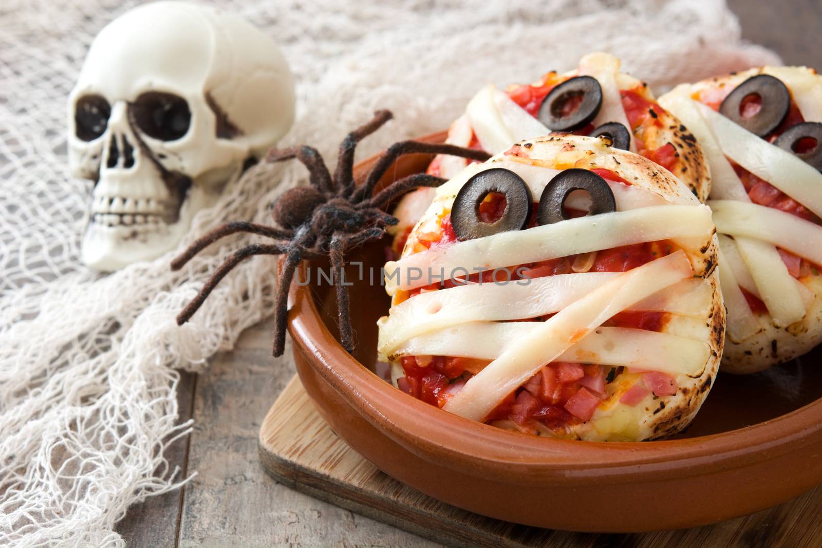 Halloween mummies mini pizzas on wooden table.