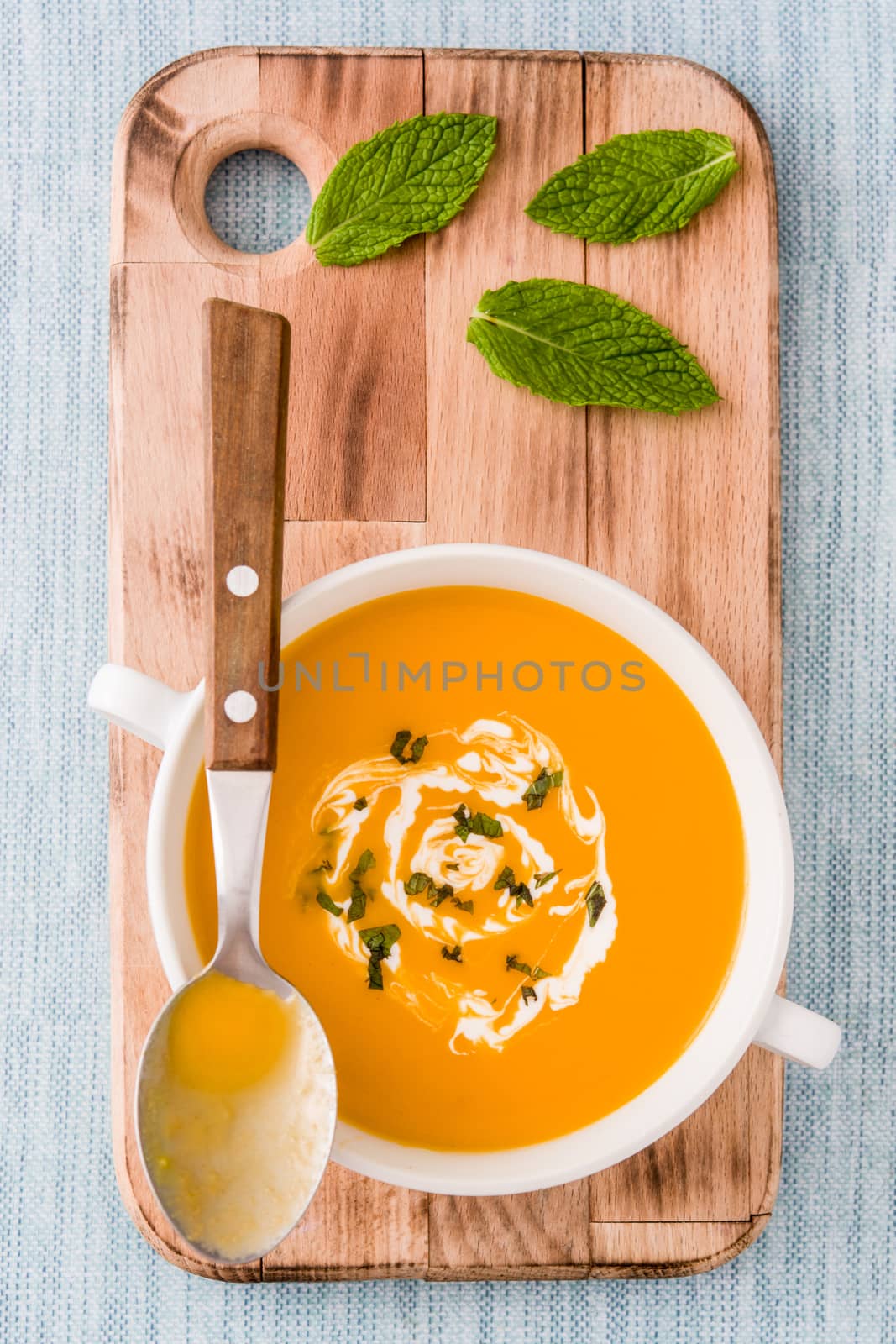 Pumpkin soup in white bowl on blue background by chandlervid85