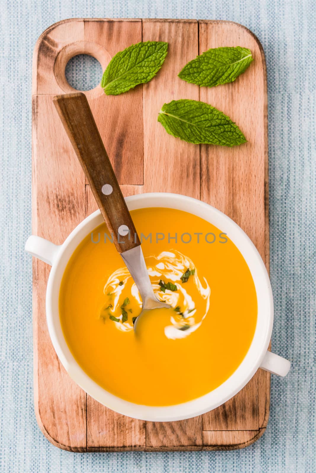 Pumpkin soup in white bowl on blue background