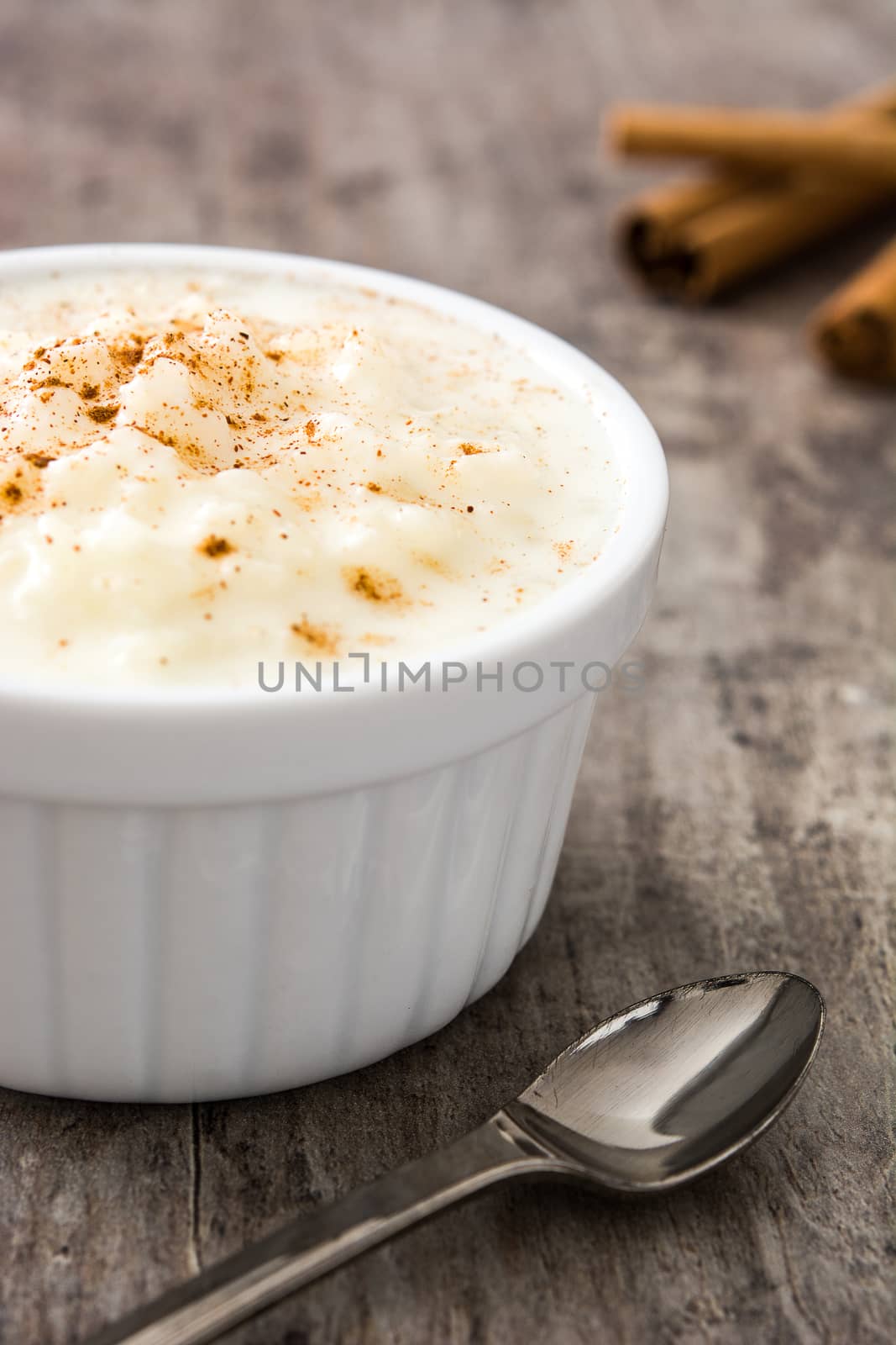 Arroz con leche. Rice pudding with cinnamon on wooden background by chandlervid85